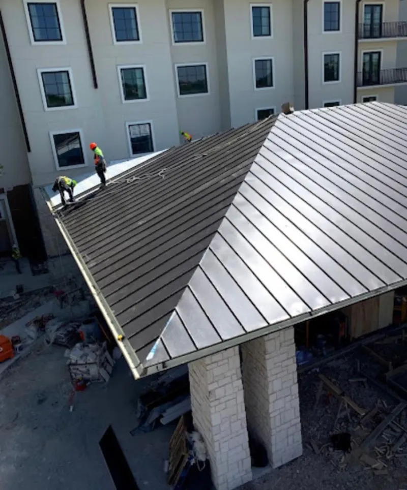 Crew installing standing seam metal roof panels on a commercial project in Polk